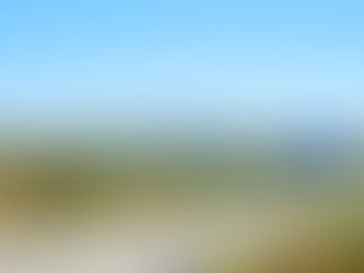 Highway with a blue sign for A2 South to Algarve, Evora, Beja. Lush green landscape and distant mountains under a clear blue sky.