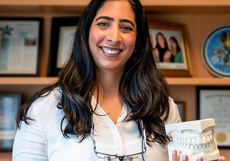 A dentist holds a model of a human jaw bone with teeth.