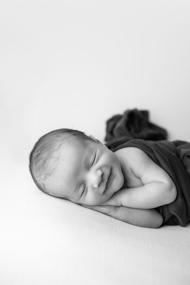 Black and white side laying newborn smiling