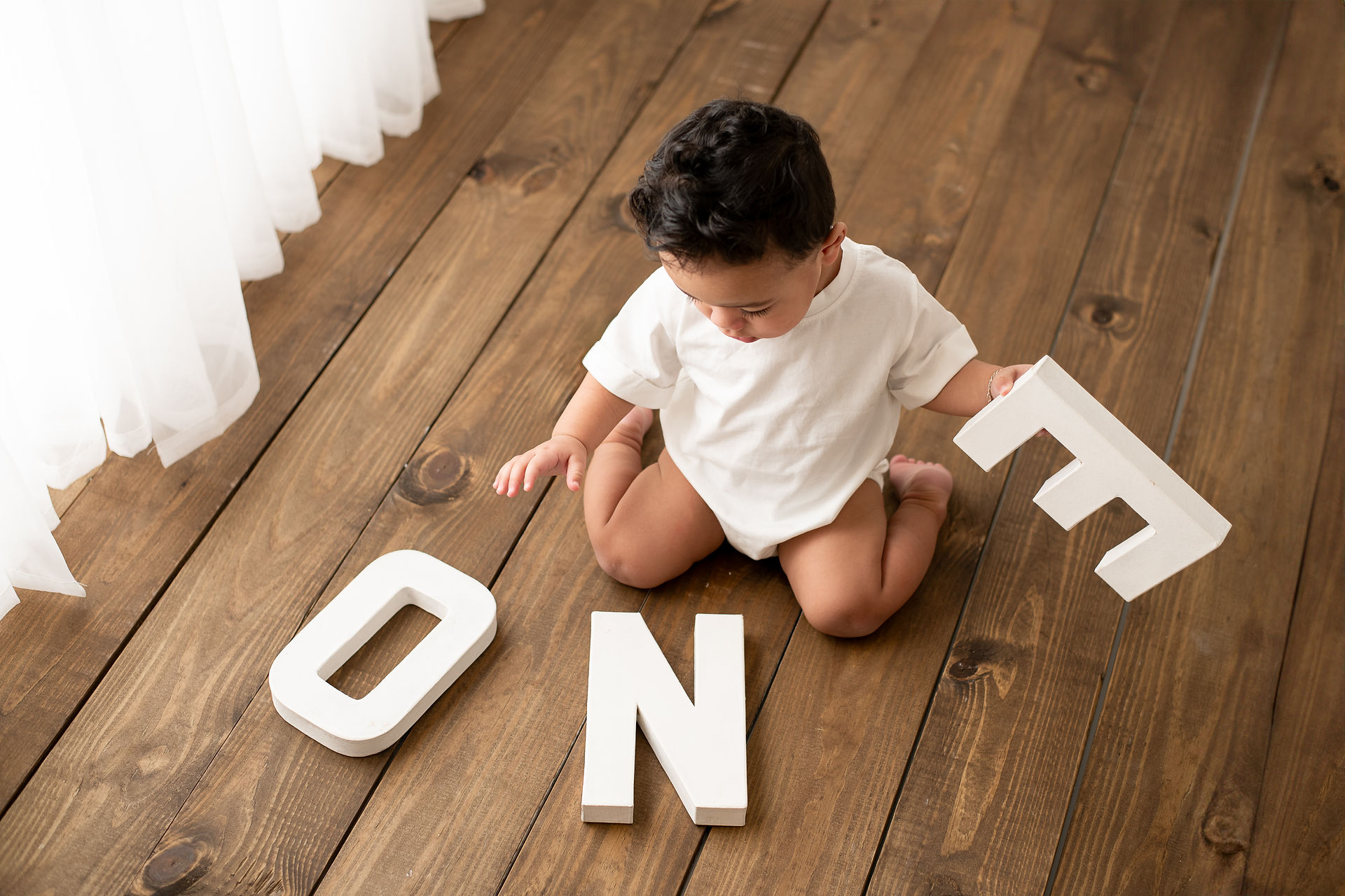 Boy looks down at ONE letters during studio photography cake smash