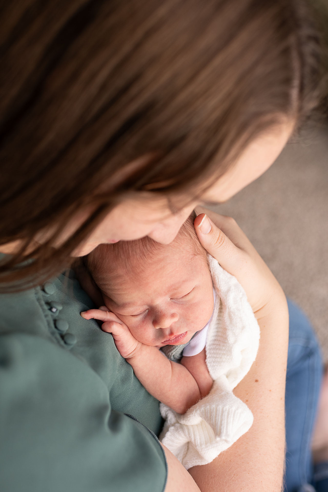 Baby boy sleeps while his mother cradles him against her. Lifestyle newborn photographer