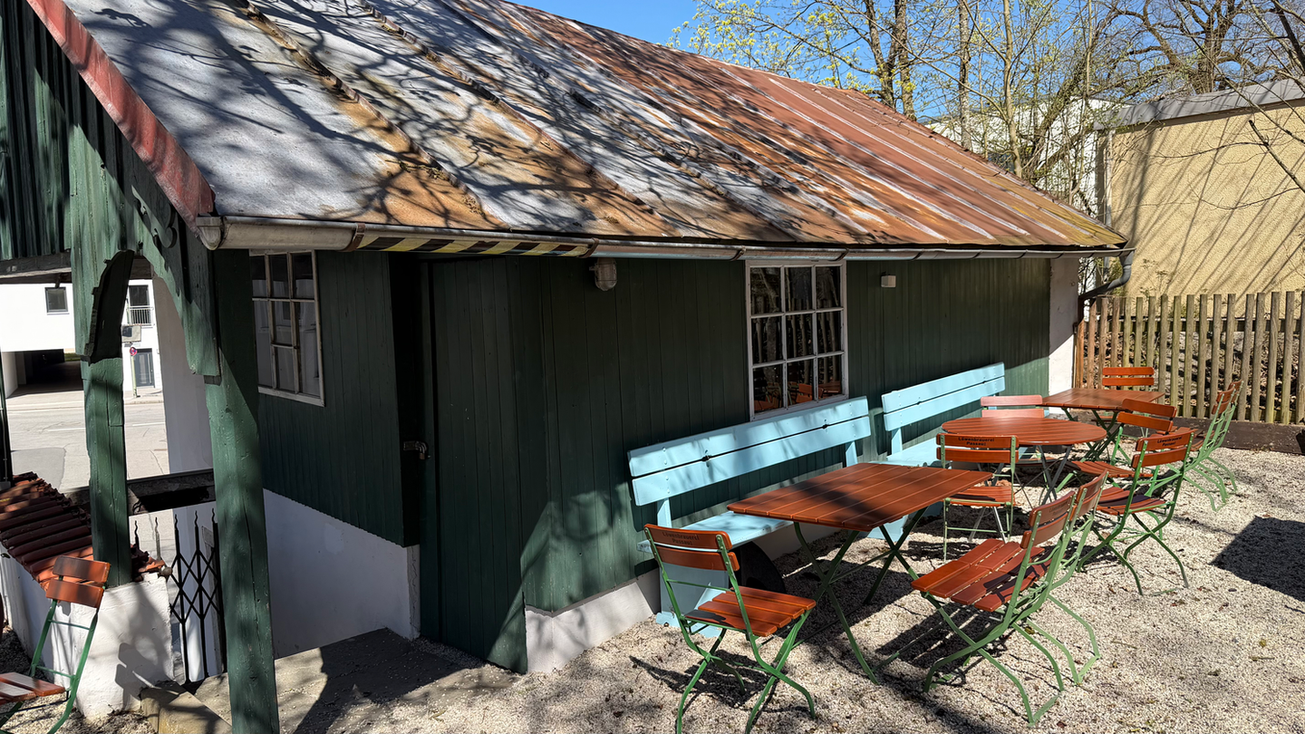 Grünes Holzhaus mit rostigem Dach und Biergartenbestuhlung