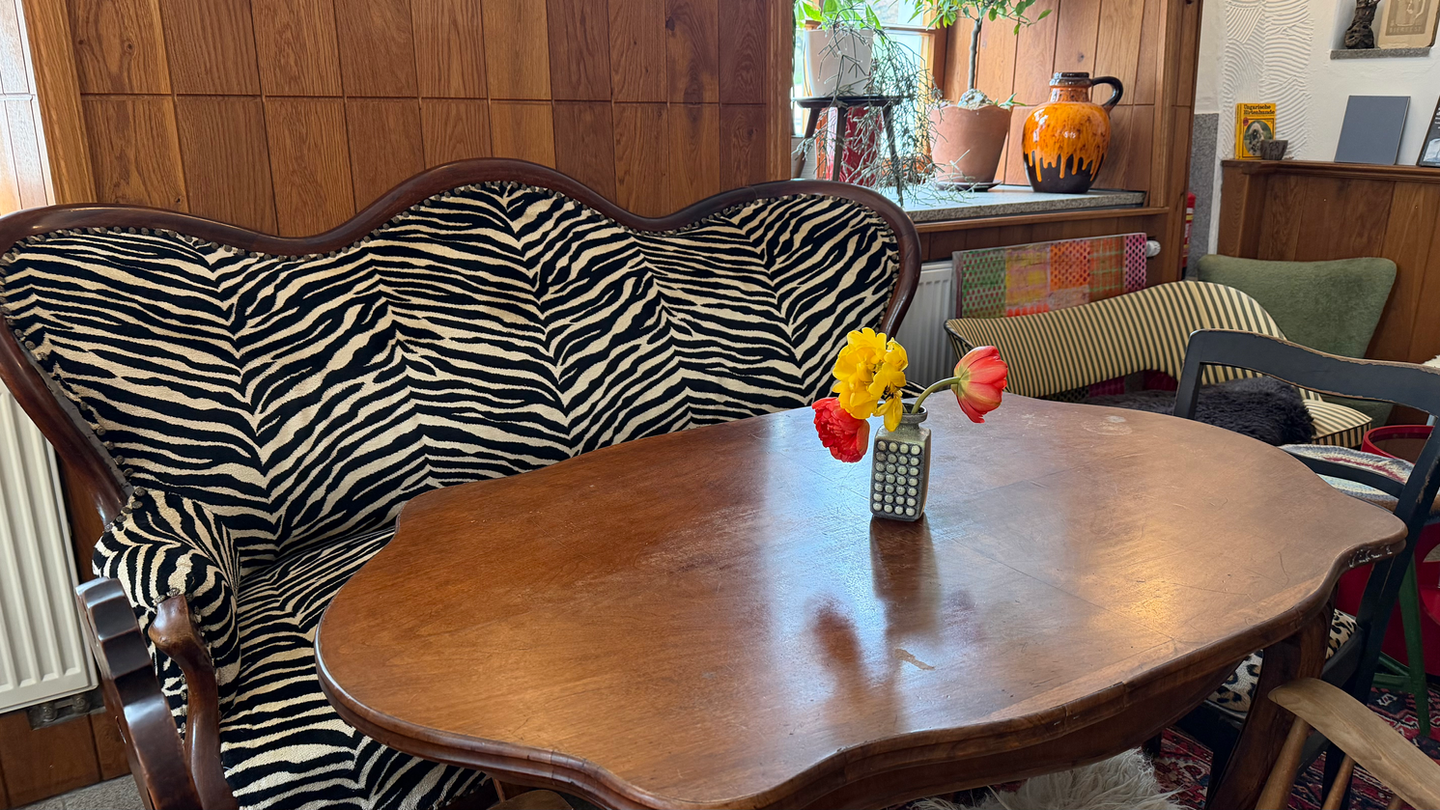 Sofa mit Zebramuster, Holztisch und Blumen.