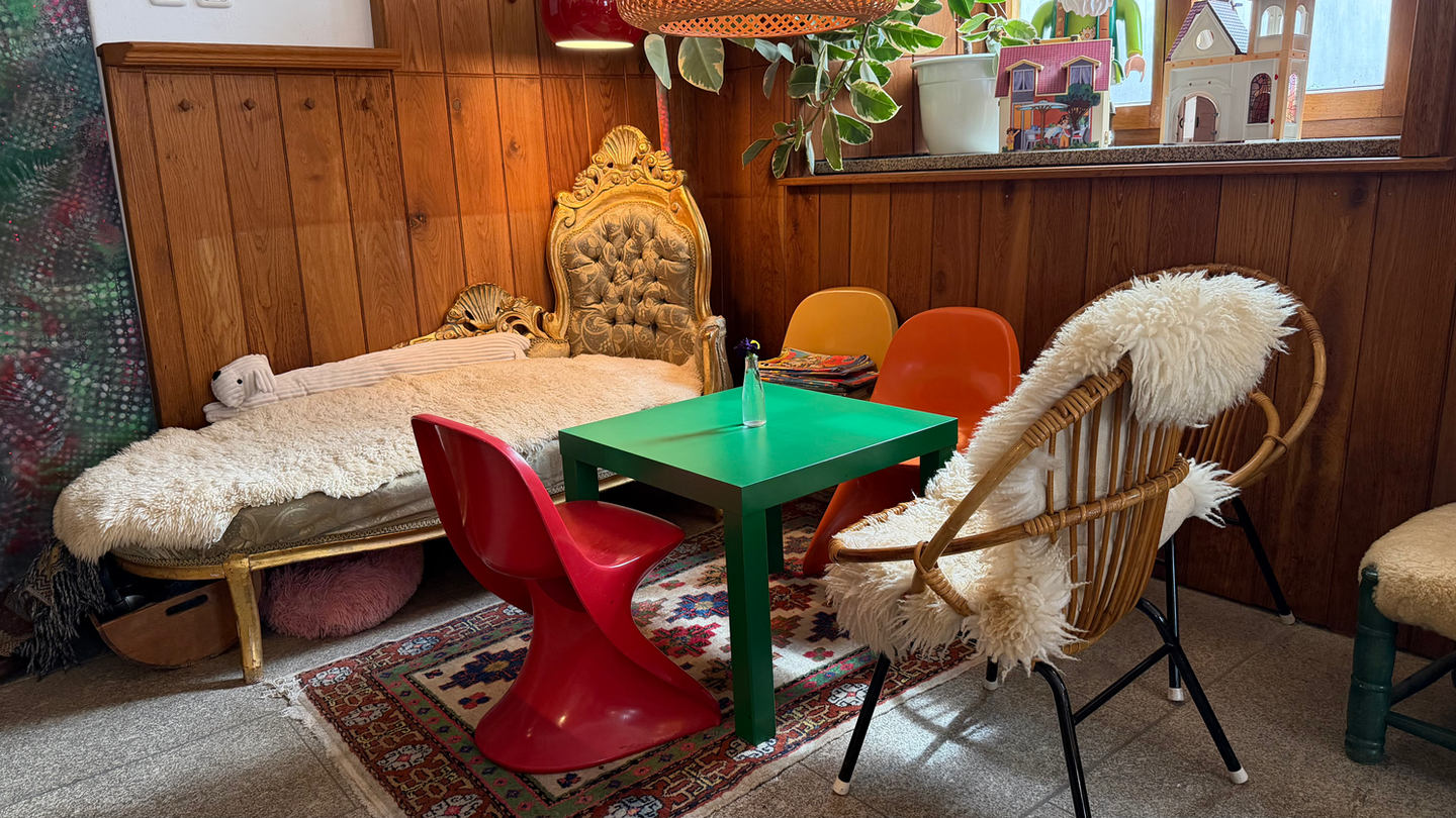 Gemütlicher Sitzbereich mit Holzwänden, Daybed und bunten Stühlen.