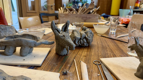 Ton-Tierfiguren mit Werkzeugen auf Holztisch