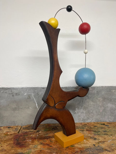 Statue en bois d'un jongleur et ses balles de couleurs.