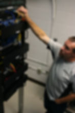 Photo of a man adjusting wires on a remote terminal computer unit.
