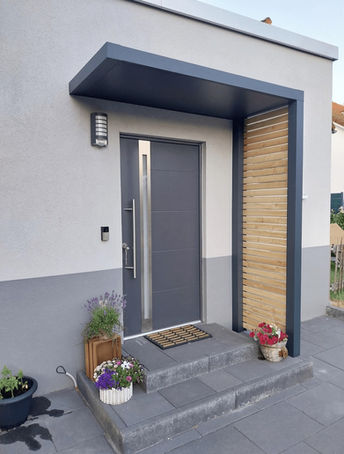 Eingangsüberdachung in L-Form mit Holzelementen an der Seite, montiert in Siegen, Paderborn und Ratingen