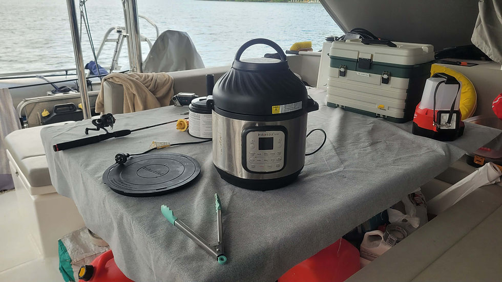 Instant Pot on a gray tablecloth in a boat cockpit, surrounded by fishing gear, a lantern, and a cooler. Water and dock visible outside.