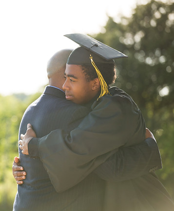 Graduate student hugging mentor outdoors, showing personal support and success in college counseling.