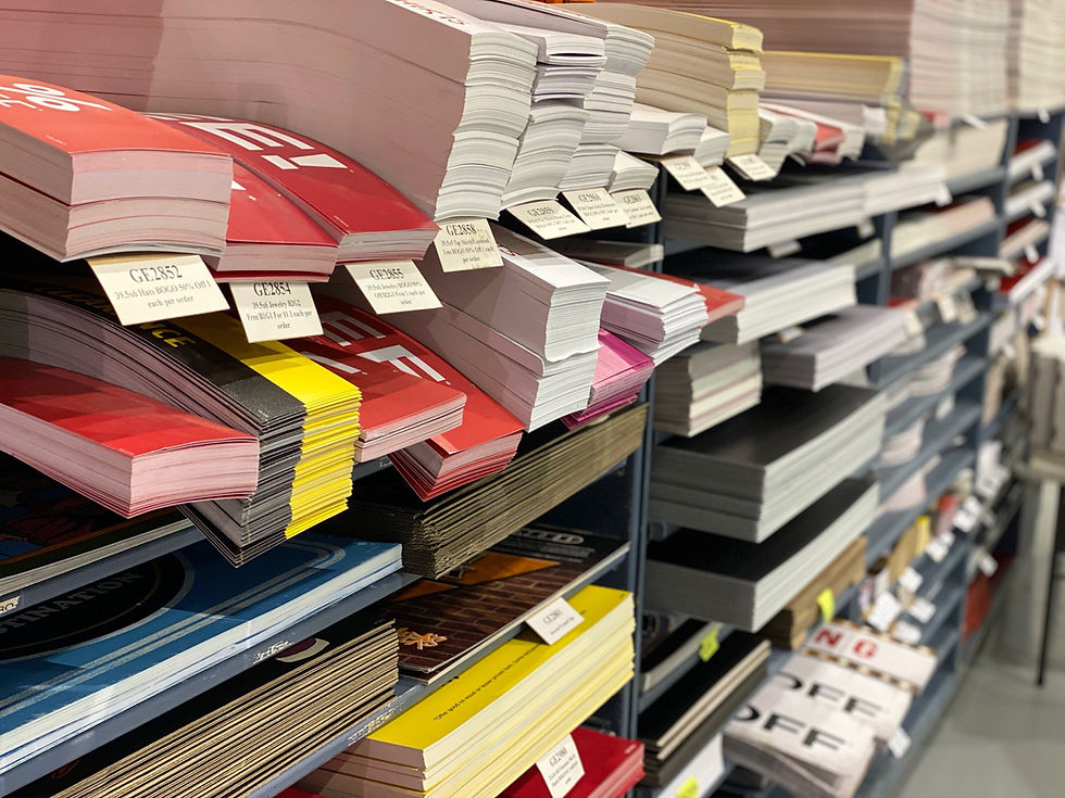 Omega Fulfillment and Warehousing center. Stacks of colorful paper on shelves in a store, with labels showing codes and pricing. The setting is organized and vibrant.