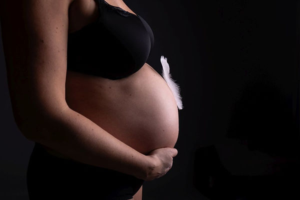 Babybauchshooting in Erding mit einer werdenden Mama und einer Feder als zartem Symbol für Leichtigkeit