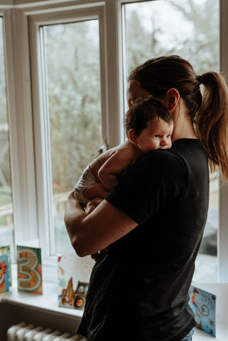 new mum and her newborn little girl cuddling, baby on mothers shoulder in leeds family photography