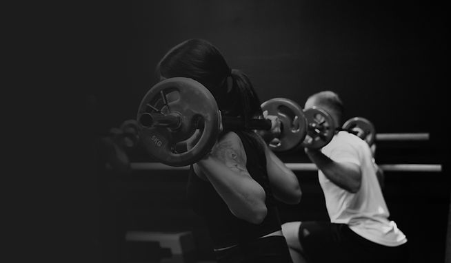Group fitness session in Vienna performing barbell back squats with weights
