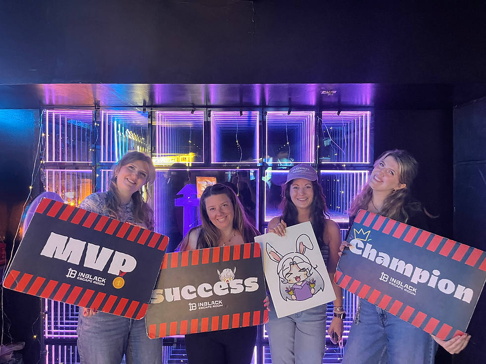 Four women celebrate their escape room success with signs