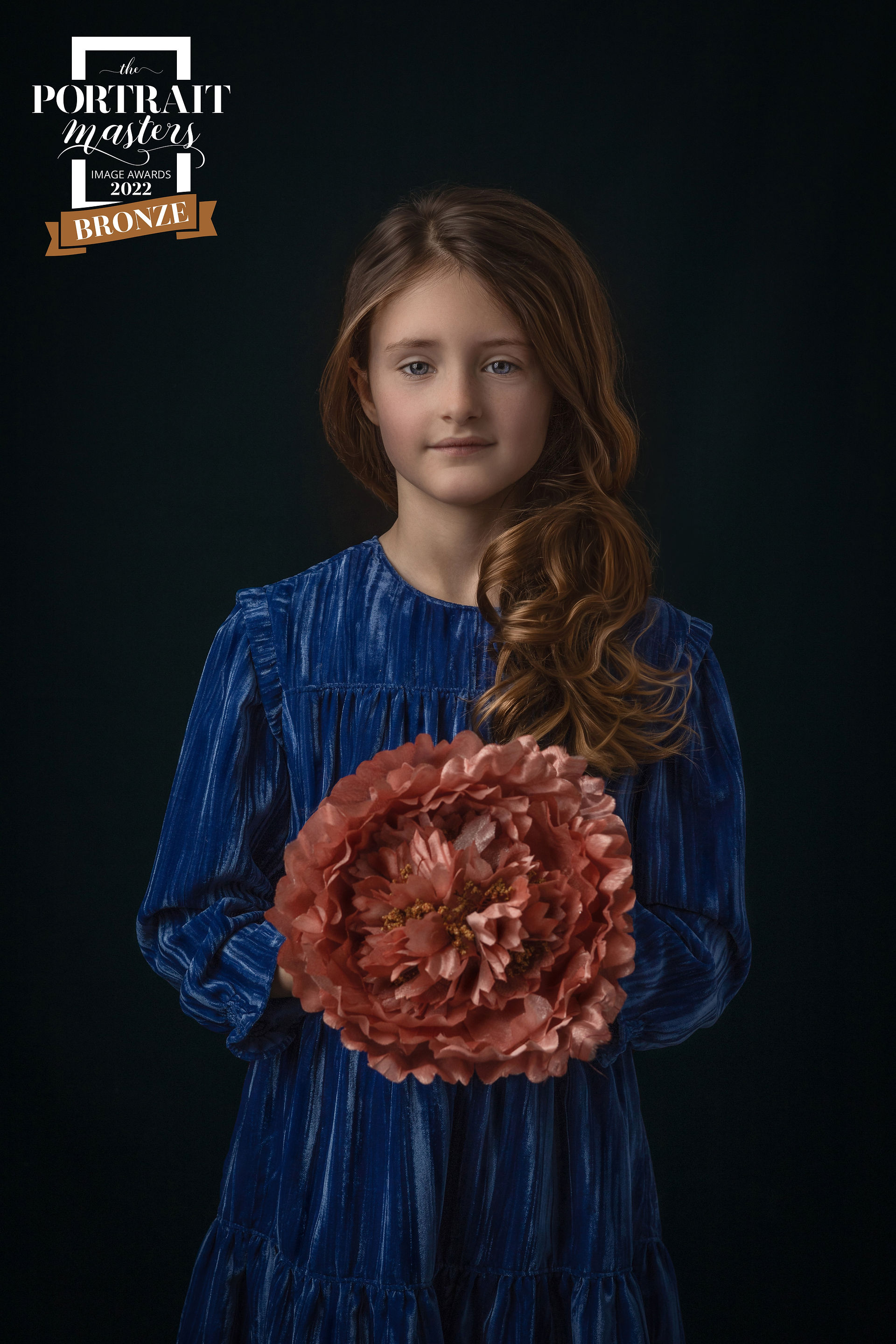 Fine Art Portrait of a young girl in blue dress holding an orange flower