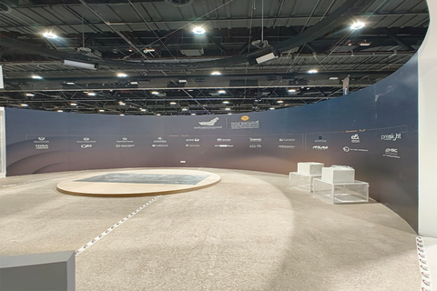 Curved exhibition booth showcasing SANDRUS TECHNICAL SERVICES and partner logos