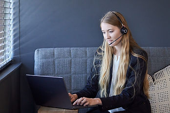 Focused young female remote worker using a headset and laptop to provide customer support, showcasing the shift towards flexible, modern work environments supported by Global Business Solutions.
