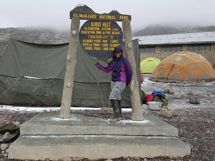 Woman standing at Kibo Hut in Kilimanjaro National Park during a mountain expedition, representing resilience, personal growth, leadership, and the journey towards achieving difficult goals.