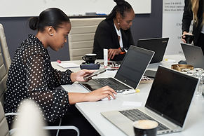 Two African professional women intensely focused on their laptops during a technology training session, demonstrating Global Business Solutions' dedication to empowering women in the tech industry through advanced training and professional development.