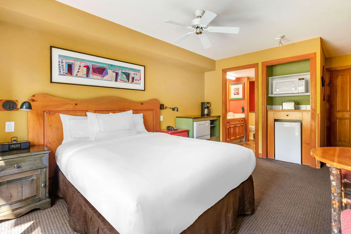 Guest room at Hilton Grand Vacations Club Whistler featuring alpine‑inspired décor, plush bedding, gas fireplace, and large windows with mountain or village views.