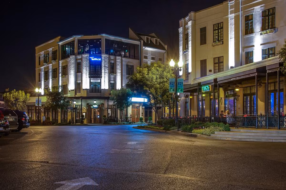 Exterior of The River Inn of Harbor Town in Memphis, Tennessee, a boutique luxury hotel with New Orleans–style architecture, wrought‑iron balconies, gas‑lit lanterns, and blooming window boxes overlooking the Mississippi River.