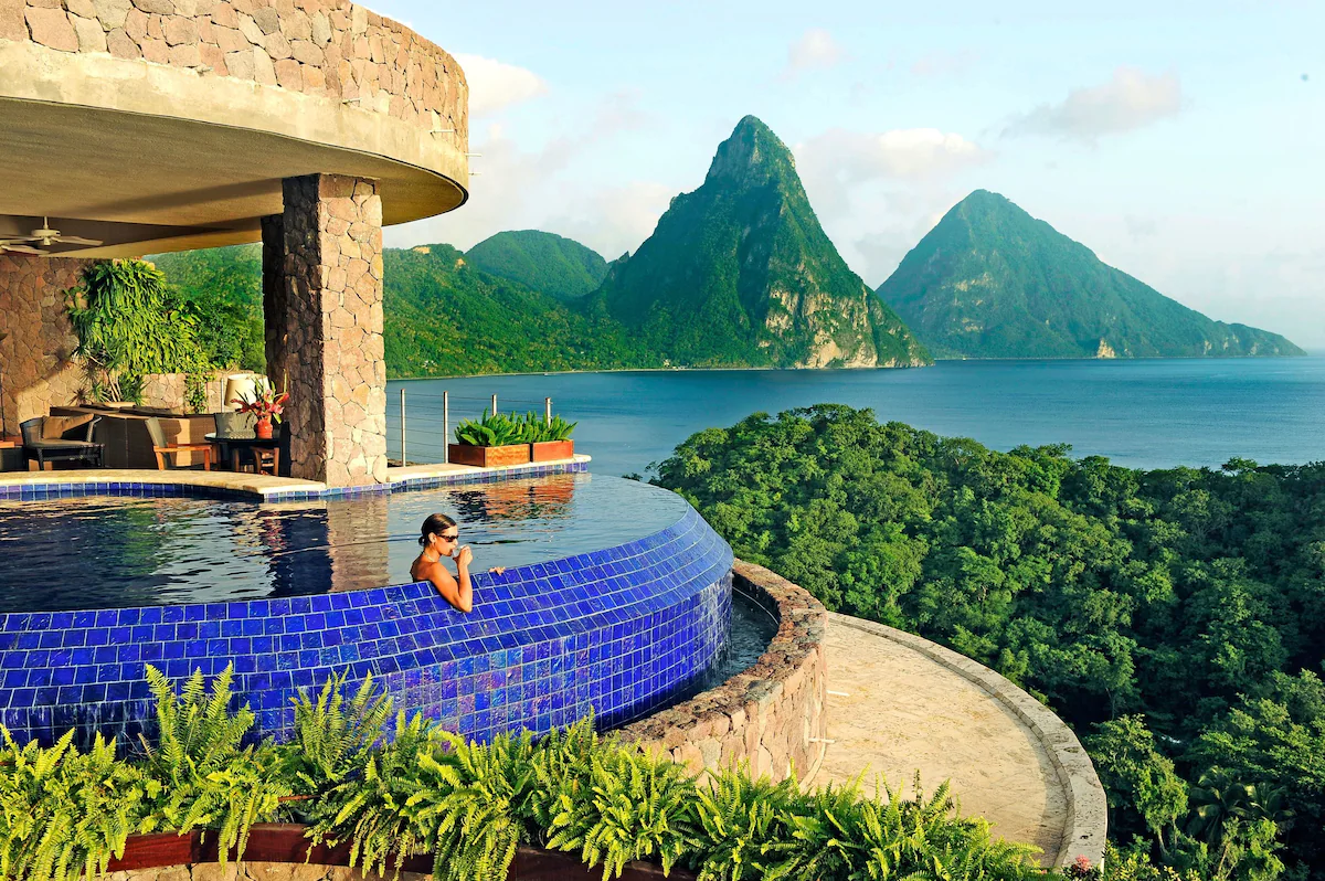 Sanctuary suite at Jade Mountain Resort in St. Lucia, featuring a private infinity pool extending toward panoramic views of the Pitons and Caribbean Sea, with open‑air architecture framed by stone columns and tropical hardwoods.