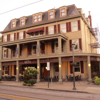 Exterior of the Chestnut Hill Hotel in Philadelphia, Pennsylvania, a historic 1894 colonial‑style building with red‑brick façade, white trim, and welcoming front entrance along Germantown Avenue in the Chestnut Hill neighborhood.