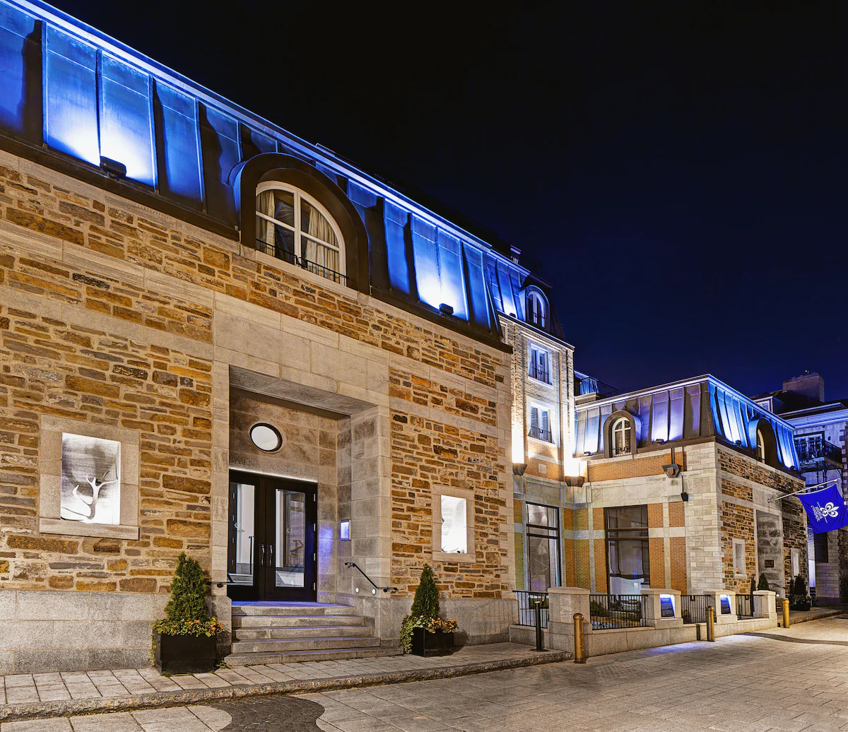 Exterior of Auberge Saint-Antoine in Quebec City’s Old Port, a boutique Relais & Châteaux hotel with historic stone façade, large windows, and modern architectural touches along the St. Lawrence River.