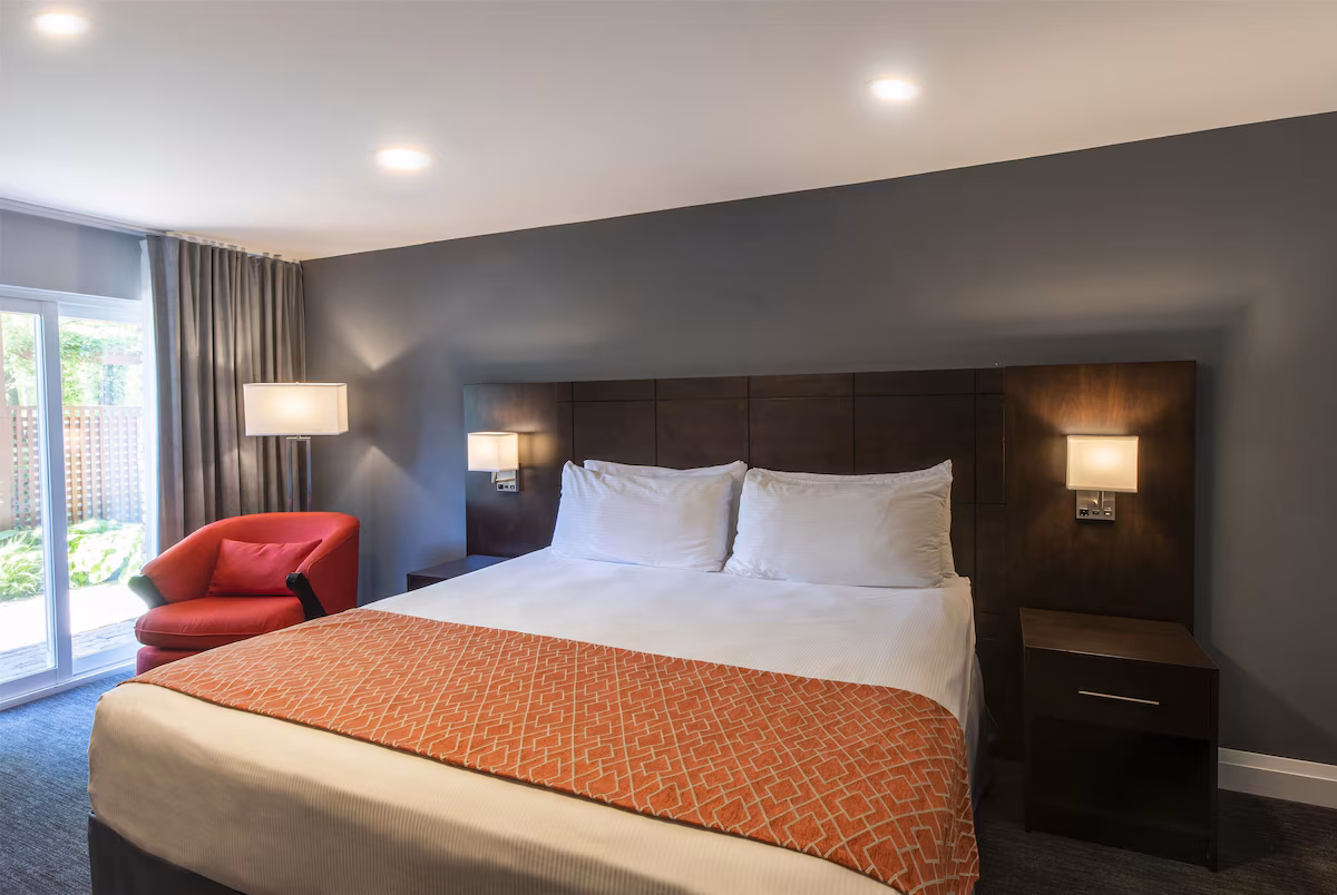 Guest room at Georgian Bay Hotel, Trademark Collection by Wyndham, featuring modern décor, plush bedding, sitting area, and large windows with natural light.