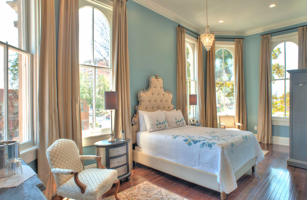 Guest room at The James Lee House in Memphis, Tennessee, featuring Victorian‑era elegance with antique furnishings, high ceilings, ornate moldings, and modern comforts blended into a historic boutique bed and breakfast.