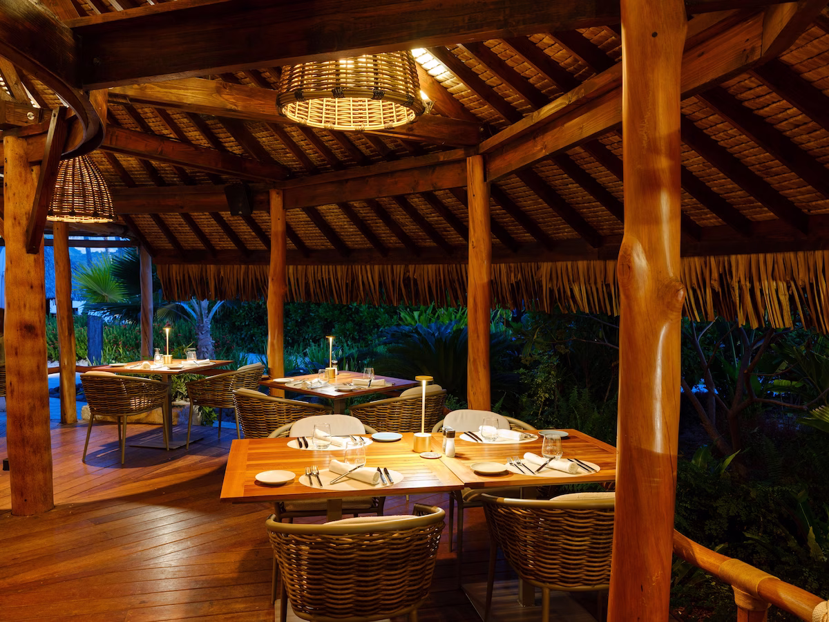 Dining at Le Bora Bora by Pearl Resorts with open‑air seating, Polynesian décor, and views of the turquoise lagoon and Mount Otemanu in the distance.
