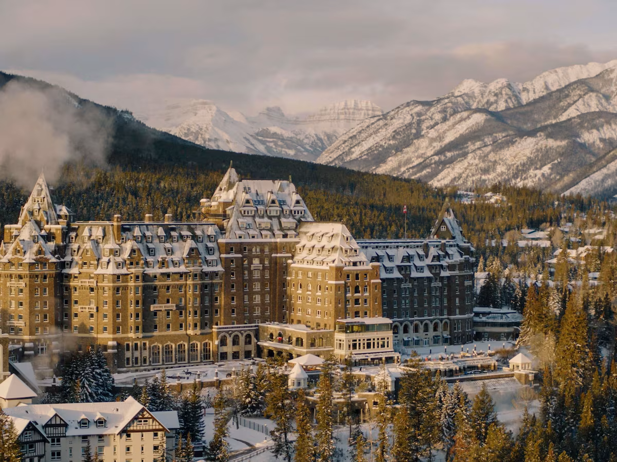 Exterior of the Fairmont Banff Springs Hotel in Banff, Alberta, Canada, a grand Scottish Baronial‑style castle nestled in the Canadian Rockies, with turrets, stone façade, and forested mountain backdrop.