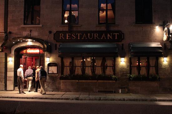 Le Continental in Old Quebec City, a classic French fine‑dining restaurant with white‑tablecloth service, dark wood furnishings, and chefs flambéing dishes tableside.