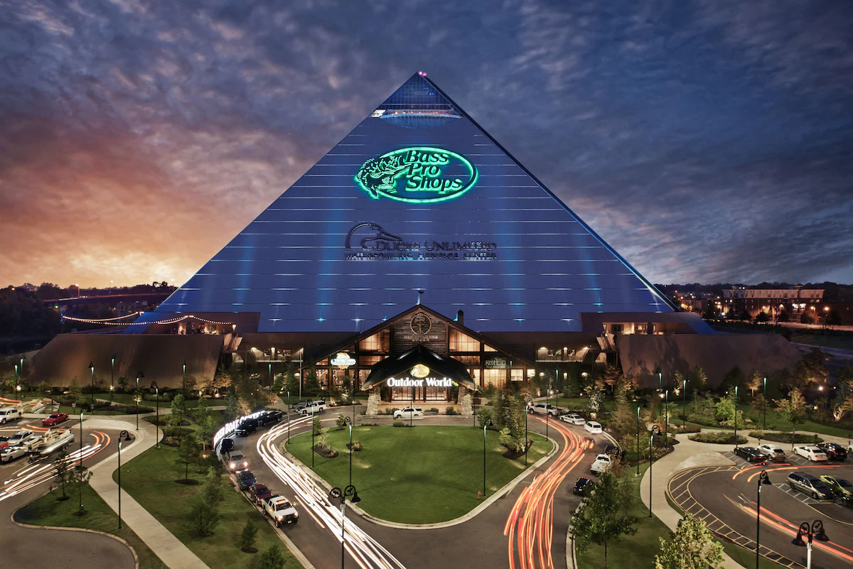 Exterior of Big Cypress Lodge in Memphis, Tennessee, located inside the iconic glass Pyramid, featuring rustic‑inspired architecture, towering structure, and Bass Pro Shops signage along the Mississippi Riverfront.