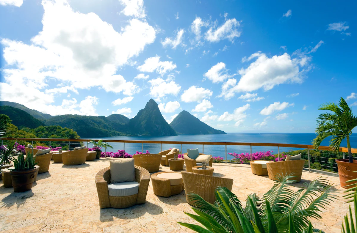Beachfront sitting area at Jade Mountain Resort in St. Lucia, with shaded lounge chairs and umbrellas set along soft sand, overlooking the turquoise Caribbean Sea and framed by views of the Pitons.