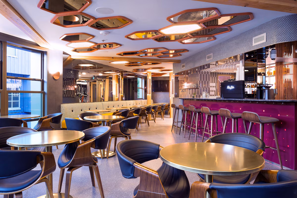 Dining at Pangea Pod Hotel in Whistler Village, featuring The Living Room café‑bar with modern alpine décor, communal seating, and a menu of brunch, coffee, and cocktails.