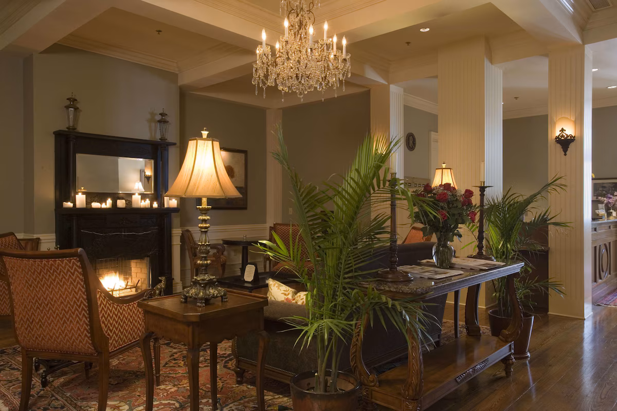 Lobby of The River Inn of Harbor Town in Memphis, Tennessee, featuring a sparkling crystal chandelier, wood‑burning fireplace, elegant furnishings, and European‑inspired décor that blends Southern charm with boutique luxury.