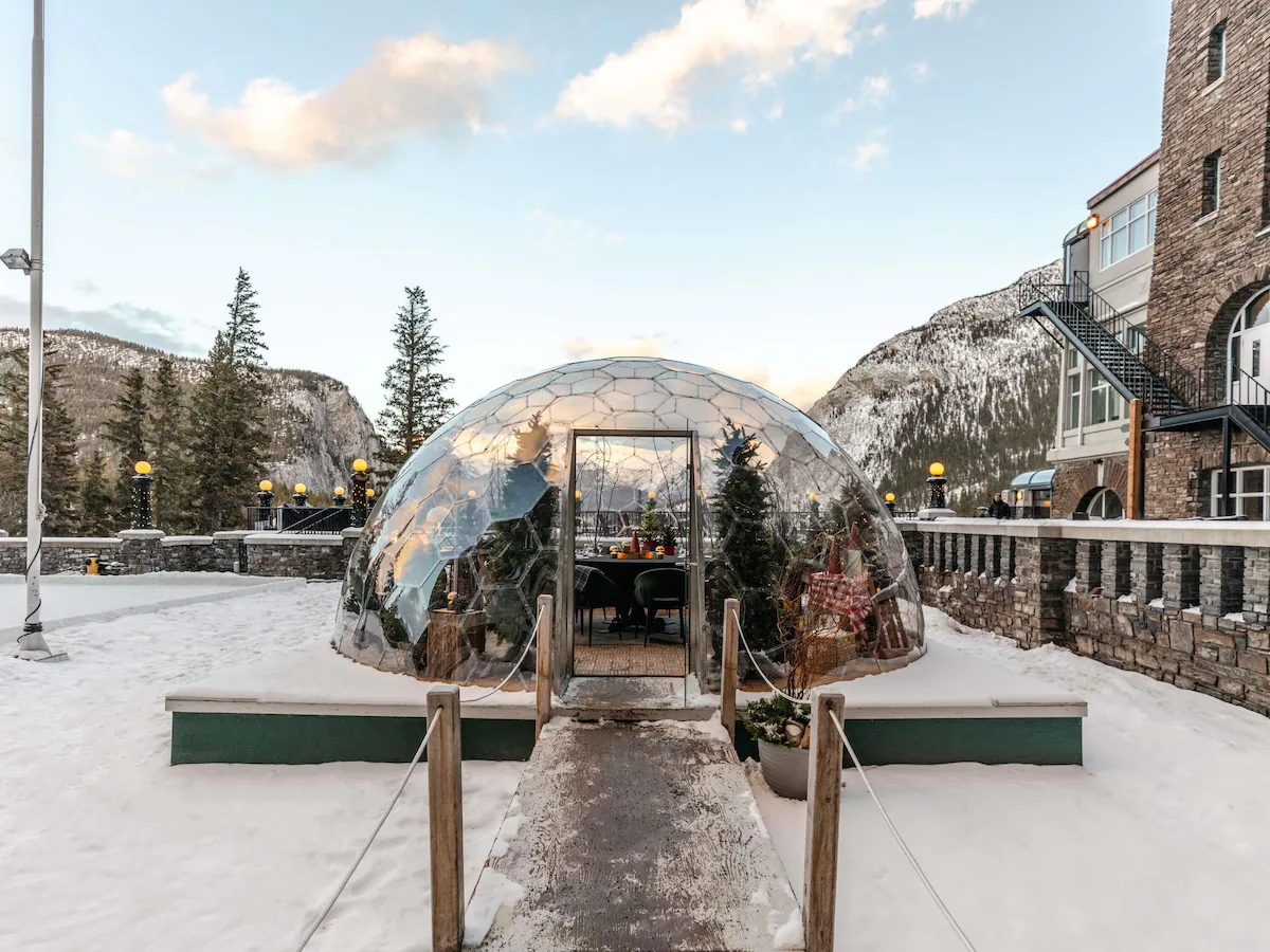 Fairmont Banff Springs Hotel 360° Dome igloo dining experience in Banff, Alberta, featuring a glass‑walled dome with panoramic views of the Canadian Rockies, elegantly set table, and cozy atmosphere for private meals under the stars.