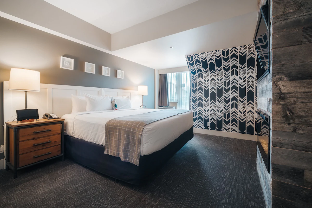 Guest room at Summit Lodge Boutique Hotel in Whistler featuring colorful, quirky décor, plush bedding, fireplace, and private balcony with village or forest views.