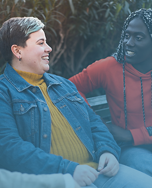 Three diverse women talking and smiling on a bench, symbolizing community and peer support.