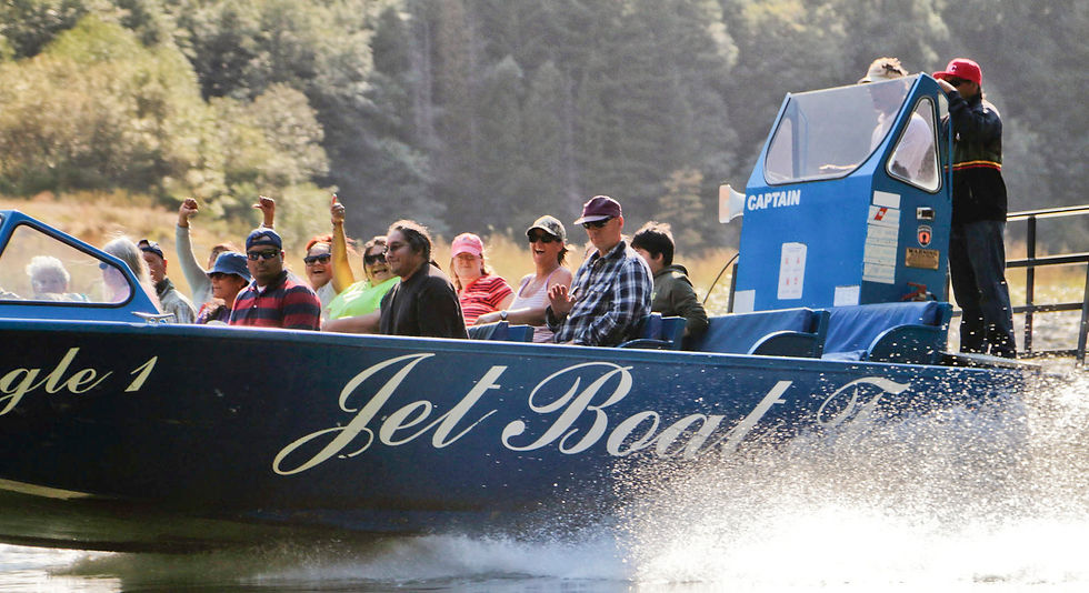 A group of people enjoying a jet boat tour on the Klamath River in Yurok Country, surrounded by lush greenery.
