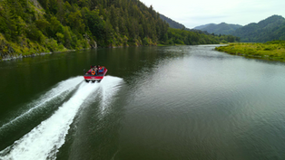 A jet boat accelerating down the Klamath River leaving behind a foamy water trail