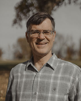 Dr. Michael Peters, founder of Let My Children Go, smiling outdoors in a plaid shirt.
