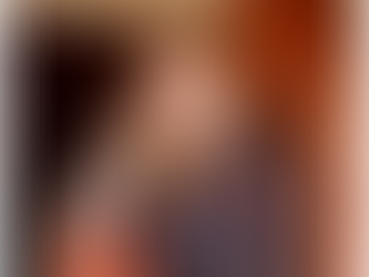 Allie sitting in an rust colored arm chair smiling.