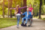 A young girl walking up to an elderly man in a wheelchair with her arms extended