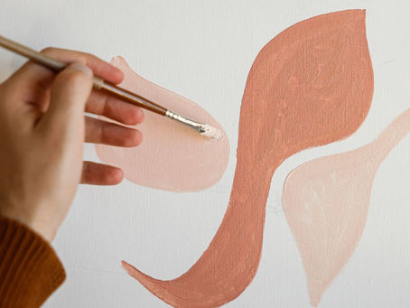 Eine Hand führt einen Pinsel mit Farbe auf Leinwand
