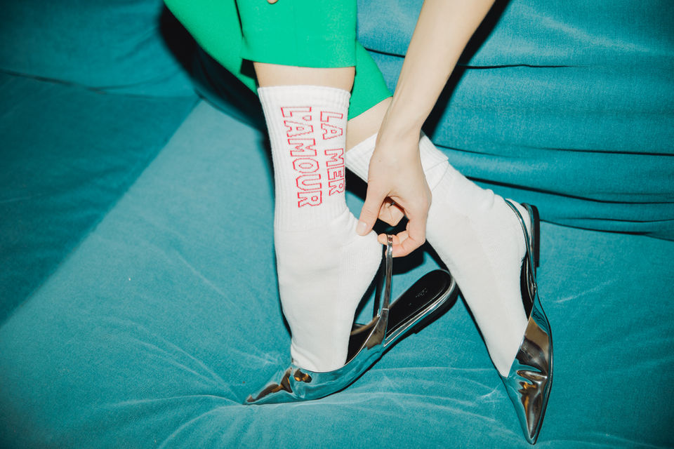 Styling Socken von Femme de Marin Model Eliza Lea auf der türkisfarbenen samtenen Couch sitzend mit silbernen Sandaletten und in grüner Hose Foto von Petra Herbert