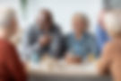 International group of positive men and women sitting around table drinking tea with cake