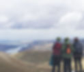 Three people linking arms at the top of a hill looking to the horizon